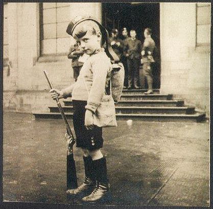 Photograph of young boy playing at being a soldier. 