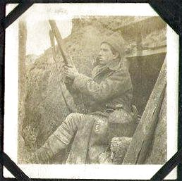 A soldier (sentry?) sits in a recess in the trench wall, his rifle at the ready.