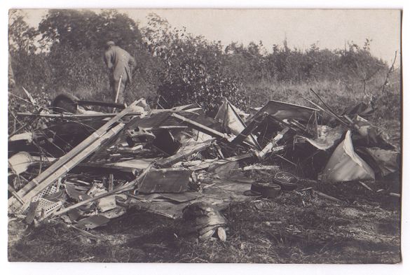 Not so fortunate. A slightly blurred figure stands on the far side of the heaped wreckage of a crashed aeroplane.