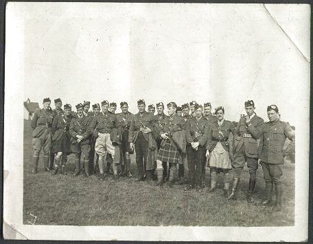 A sunny day out on the heath. A large group of men wearing a variety of uniforms stand in an informal group for this photograph.