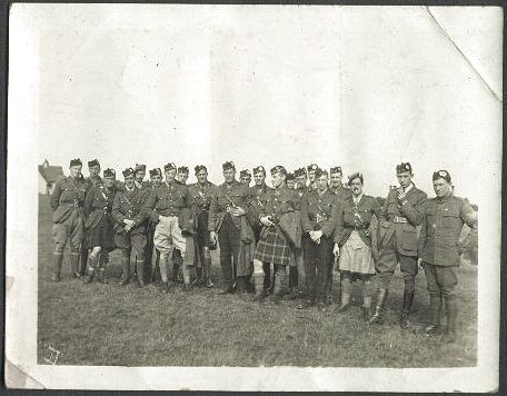 A sunny day out on the heath. A large group of men wearing a variety of uniforms stand in an informal group for this photograph.