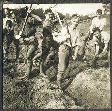 A bright sunny day, and half a dozen energetic young men tackle the job of digging a trench.  Possibly at training base?