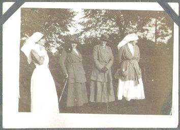 Four women in uniform standing on a lawn.