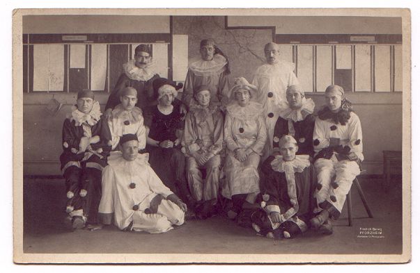A formally posed group photograph, but all are wearing pierrot costumes.