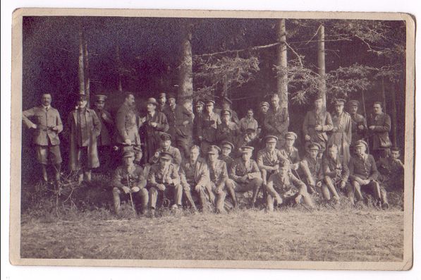 A large group seated in the shade of the trees.
