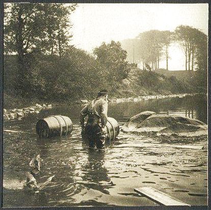 Looks like it capsized!  One man stands, thigh deep in the water, contemplating a mess of planks and oil drums which no longer resemble a bridge.