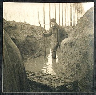 A soldier wades through the knee deep water in the trench.