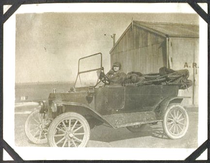 A WRAF driver at the wheel of an open-topped staff car.