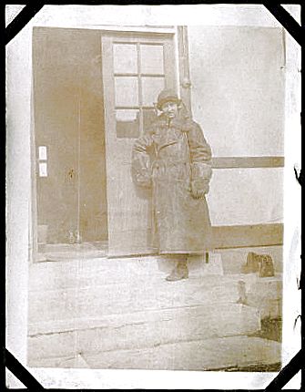 A fully outfitted WRAF motorcycle driver stands at the entrance to a hut.